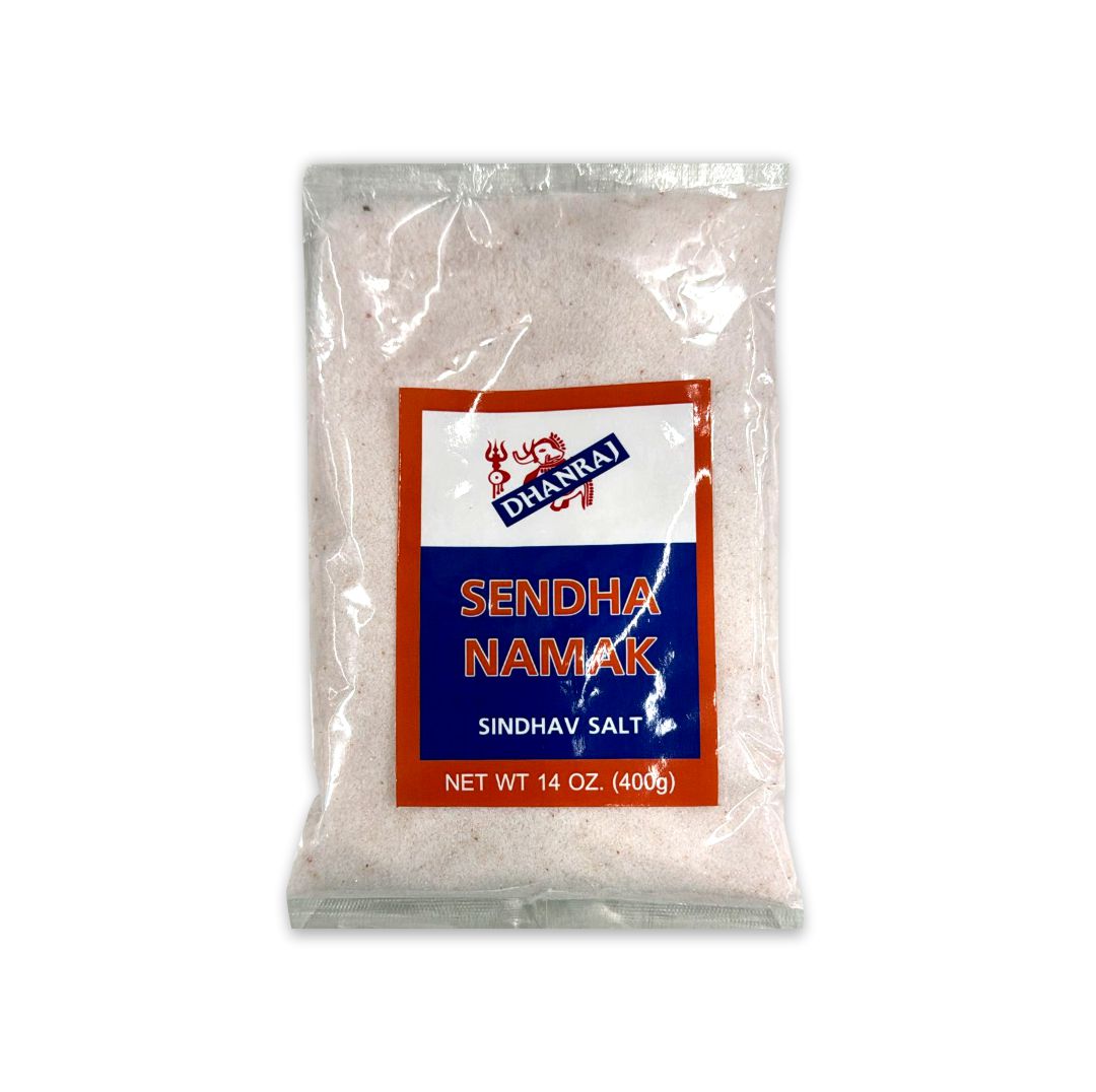 Clear package of Dhanraj Sendha Namak showing pinkish-hued granular rock salt through the transparent bag.
